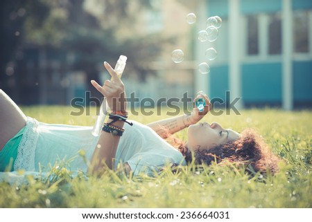 young beautiful moroccan curly woman blowing bubbles at the park