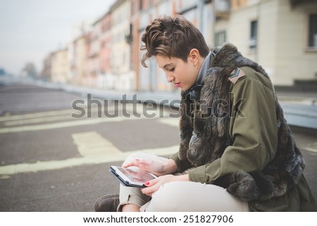 young beautiful short hair hipster woman in town using tablet technological device connected wireless