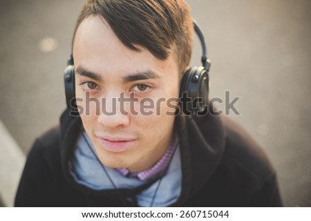 young crazy funny asian man in town outdoor lifestyle listening music with headphones