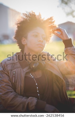 beautiful black curly hair african woman listening music with headphones in town