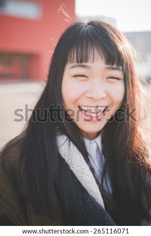 young beautiful asian hipster woman in the city - living town during sunset in backlit smiling happy