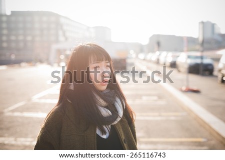 young beautiful asian hipster woman in the city - living town during sunset in backlit