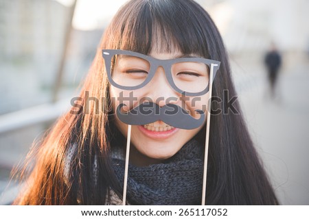 young beautiful asian hipster woman in the city - with funny fake eyeglasses and moustache