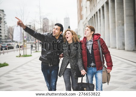 Multiracial group of two men and woman friends outdoor in town happy walking hugging