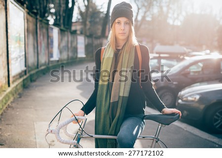 young beautiful hipster sporty blonde woman in town with bike