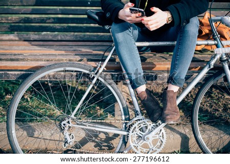 close up legs and hands young hipster sporty blonde woman in town with bike using smartphone