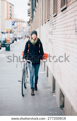 young beautiful hipster sporty blonde woman in town with skate and bike
