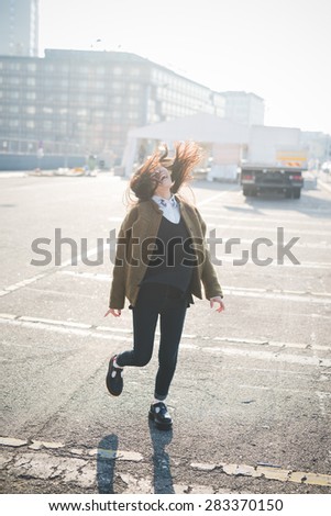 young beautiful asian hipster woman in the city - living town during sunset in backlit jumping and dancing
