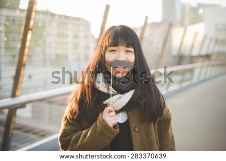 young beautiful asian hipster woman in the city - with funny fake moustache