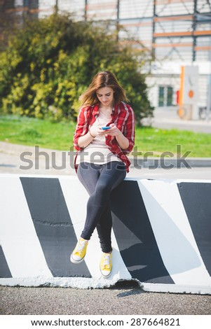 young beautiful blonde hipster woman in the city using smartphone connected online wireless