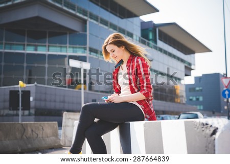 young beautiful blonde hipster woman in the city using smartphone connected online wireless