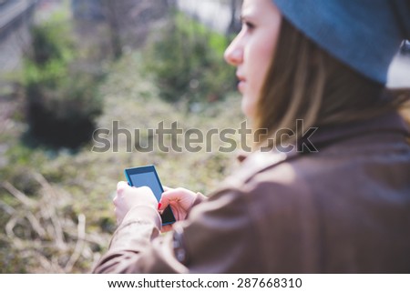 young beautiful blonde hipster woman in the city using smartphone connected online