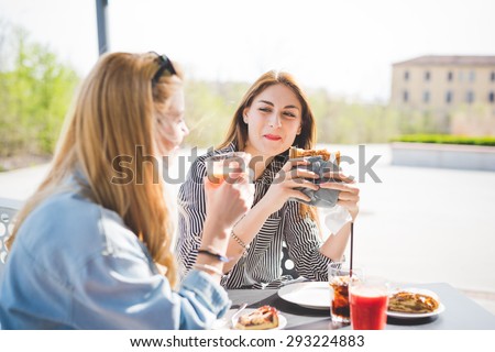 Two young handsome caucasian and eastern women having an happy hour in a bar - happy hour, relax, friendship concepts