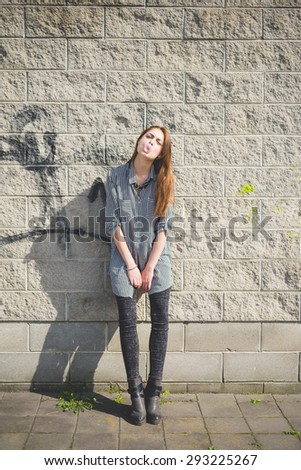 Young handsome brunette eastern fashion girl posing leaning on a wall in the city suburbs