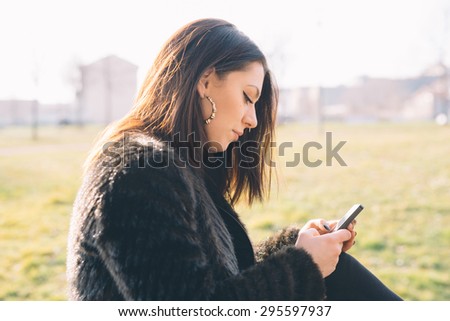 Young handsome brunette caucasian girl using a smartphone connected online in a park in the city. technology, connectivity, e-commerce- business, social network concepts