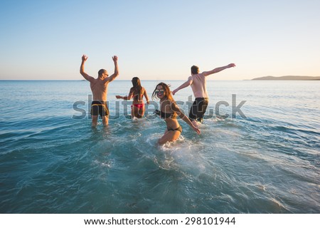 group of young multiethnic friends women and men at the beach in summertime taking a bath having fun in the sea