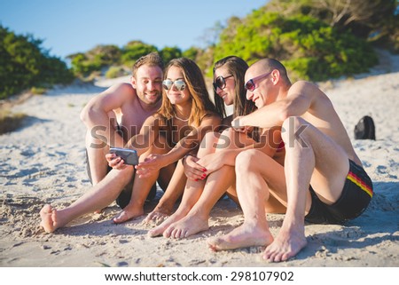 Group of young multiethnic friends with digital tablet sitting at the beach -  multi cultural friendship and social media networking concepts - Interaction with new trends and technological devices