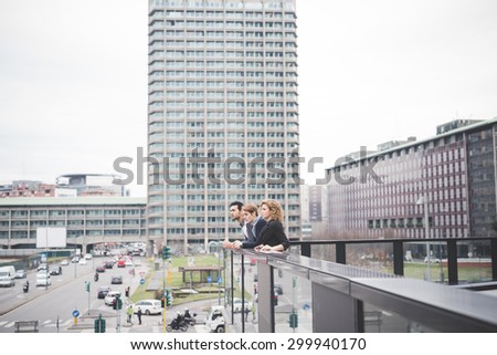 Multiracial contemporary business people leaning on a balcony in town, overlooking - finance, business, future concept
