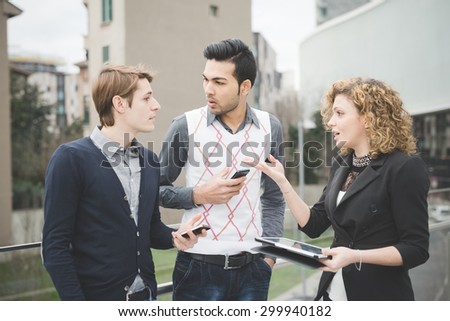 Multiracial contemporary business people working outdoor in town connected with technological devices like smartphone and tablet, talking to each other  - business, finance, technology concept