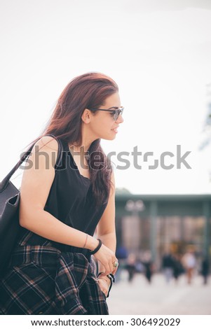 Knee figure of a young beautiful reddish brown hair caucasian girl with sunglasses smiling overlooking right - carefreeness, freshness, youth concept - dress with black shirt