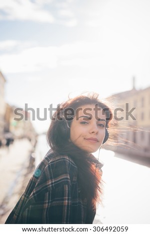 Half length of young beautiful reddish brown hair caucasian woman listening to the music seated on the sidewalk - relax, music, technology concept - dressed with black shirt, overlooking left