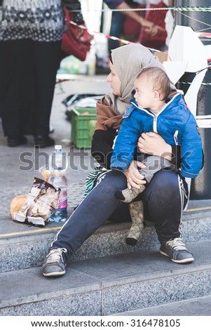 BUDAPEST - SEPTEMBER 7 : War syrian refugees at the Keleti Palyaudvar Railway Station on 1 September 2015 in Budapest, Hungary. Woman hugging tightly her baby, with bottle of water and wafer