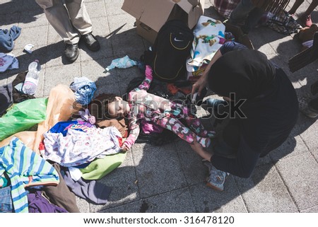BUDAPEST - SEPTEMBER 7 : War syrian refugees at the Keleti Palyaudvar Railway Station on 1 September 2015 in Budapest, Hungary. Woman wearing her babies falling asleep on the floor, arms wide open.