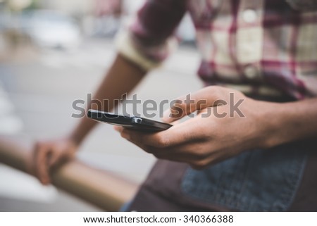 Close up on the hand of a young handsome afro black man using a smartphone, tapping the screen - technology, social network, communication concept