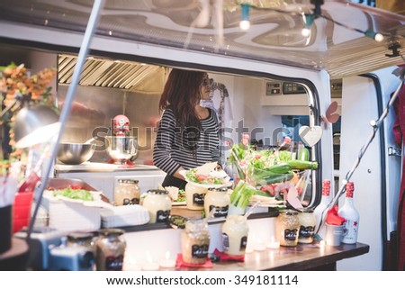 MILAN, ITALY - NOVEMBER 7: People visiting Eat Market, a street food parade with international dishes  in Milan on November, 7 2015. Woman inside her food truck waiting for customer