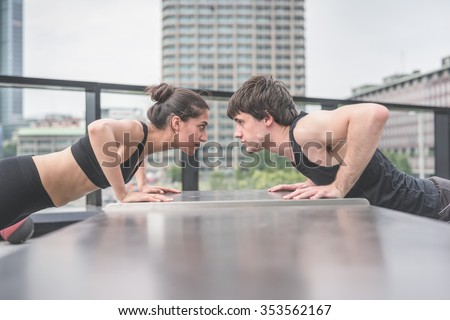 Couple of young handsome caucasian sportive man and woman doing push ups, facing each other, staring at each other\'s eyes - sportive, fitness, healthy, training concept