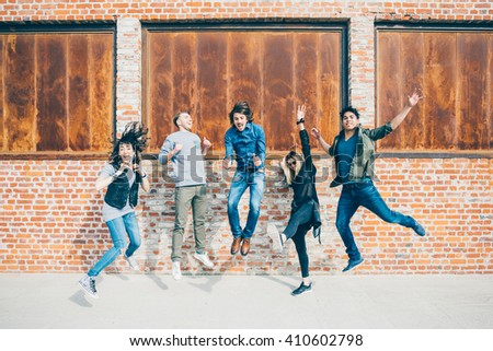 Group of young beautiful multiethnic man and woman friends having fun jumping outdoor in the city - happiness, friendship, teamwork concept