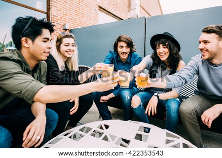 Group of young multiethnic friends sitting in a bar toasting, talking to each other, having fun - happy hour, friendship, relax concept