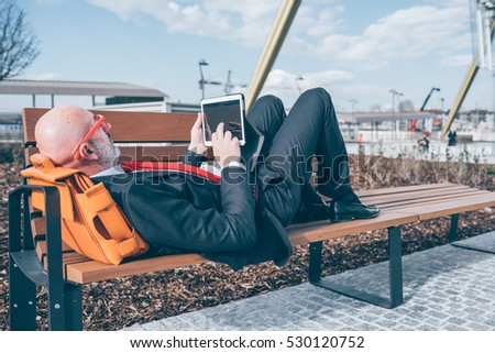 Middle age caucasian businessman relaxing lying down on a bench using tablet - relax, business, resting concept