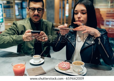Young couple photographing food with smart phone - social network, sharing, food blogger concept