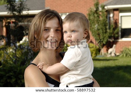 Young mother and her little son play in the garden.