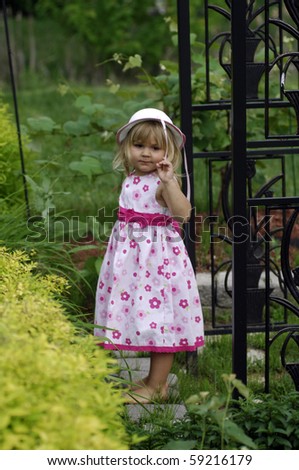 A cute little girl wearing dress plays in the garden.