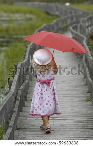 stock photo : Little blond girl with the red umbrella walks on the boardwalk.