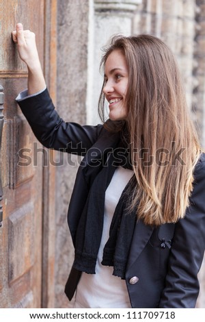 Smiling girl knocks on the closed door of the church
