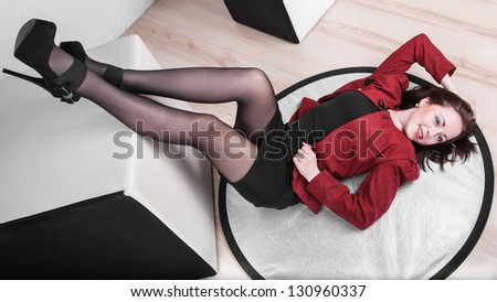 Leggy girl posing in studio laying on the floor with legs raised up, 16 9 ratio
