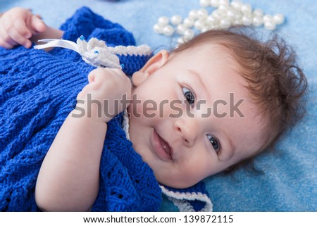 Portrait of baby girl fashionista in a knitted dress on a blue background
