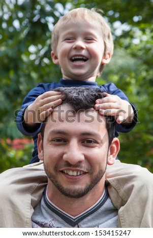 Father Giving Son Ride On Back In Park