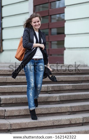 Young smiling woman holding a shoes on stairs