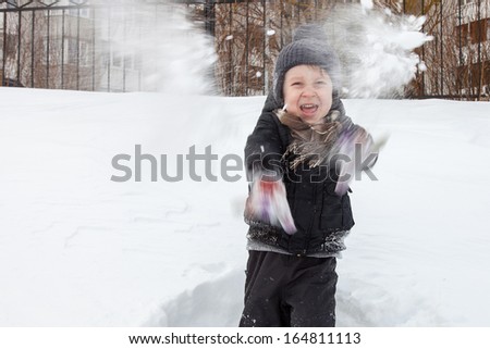 Young boy in knitted hat throws snowballs