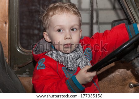 Boy playing behind the wheel of an old car