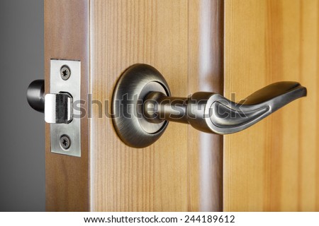 Slightly opened wooden door with latch handle closeup