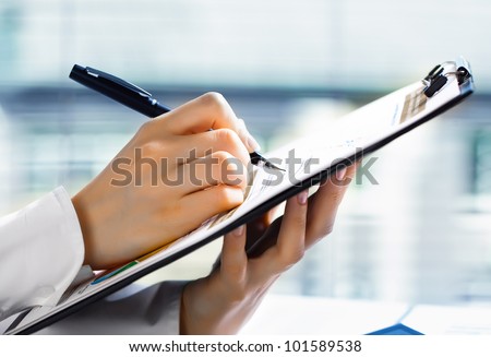 Accounting. Woman's hand with a pen writing on the business paper