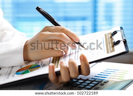 Accounting.Woman's hand with a pen writing on paper