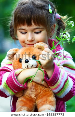 Pretty smiling girl playing with teddy bear soft toy