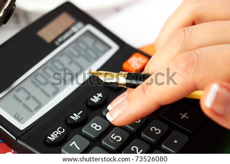 Female  hand  with a calculator and a pen, business  graphics, and  Diagram.
