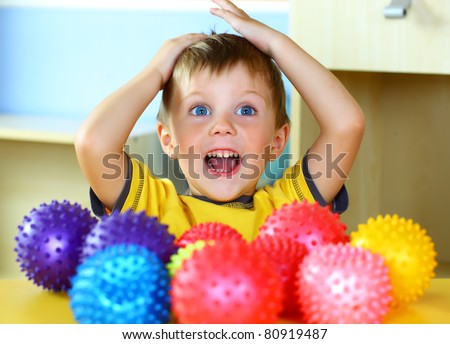 A boy plays with rubber colored balls